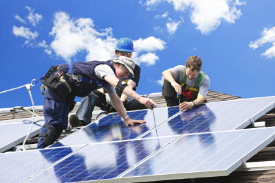 workers installing solar panels on roof
